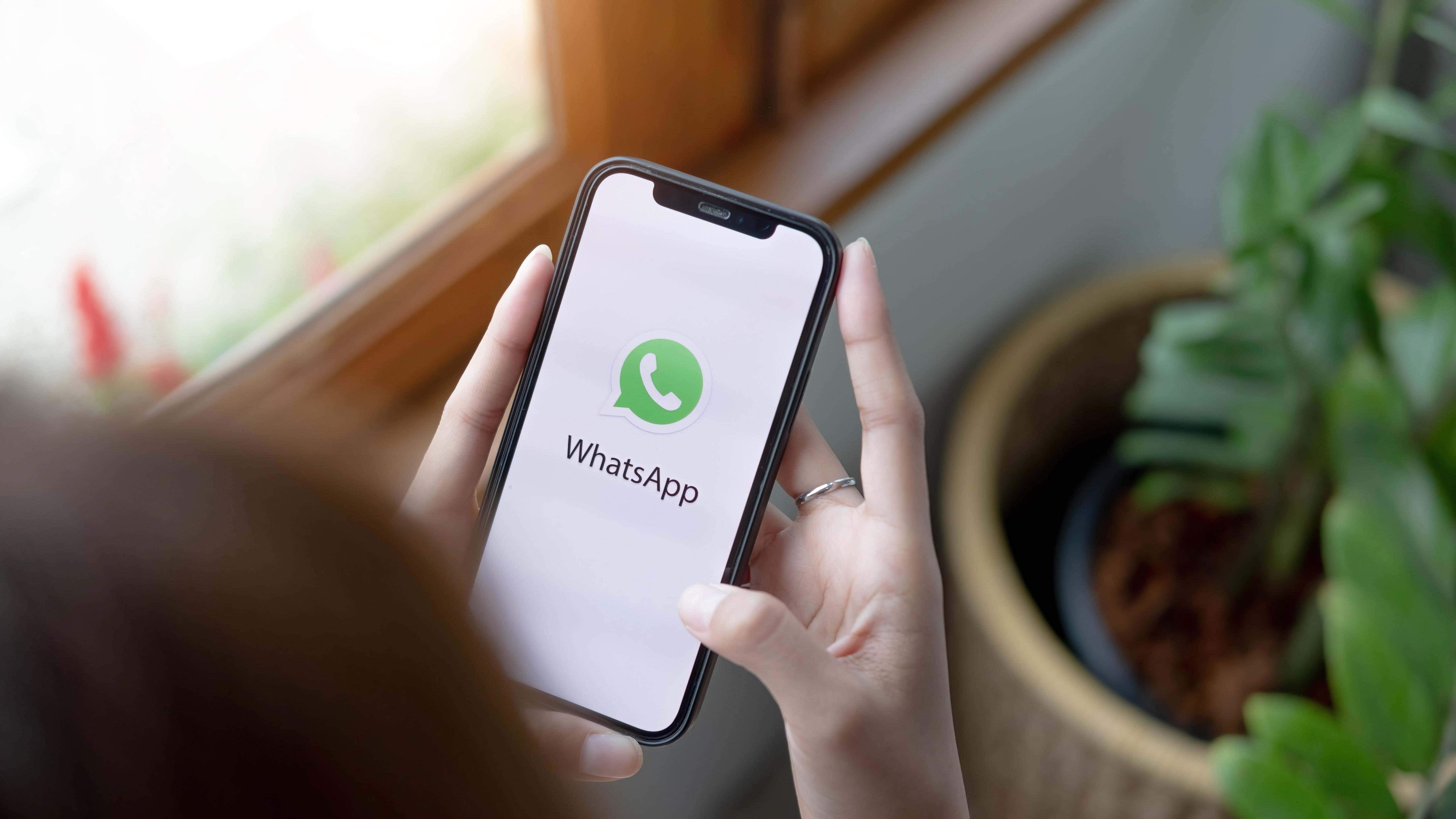 Persona que sostiene un teléfono inteligente y abre WhatsApp